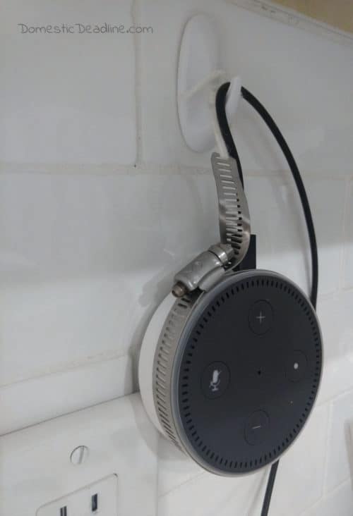 An easy and inexpensive way to hang your Amazon Alexa Dot on the wall near the outlet. This DIY Alexa Dot Holder uses a hose clamp and command hooks. Upcycle Challenge www.domesticdeadline.com