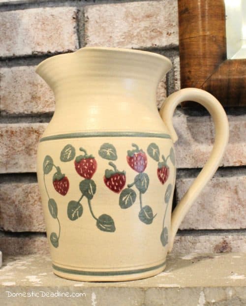 Learn how a few coats of paint can easily transform an old dated ceramic pitcher into a classic farmhouse pitcher full of greenery for mantel decor. DomesticDeadline.com