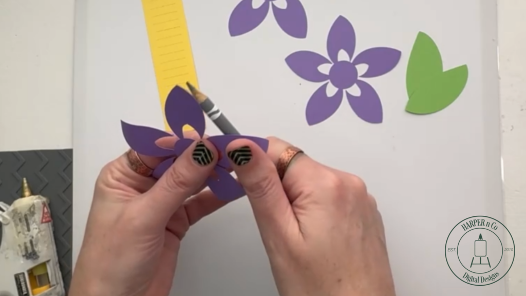 Shaping petals on the largest layer of a layered 3D paper flower using a pencil