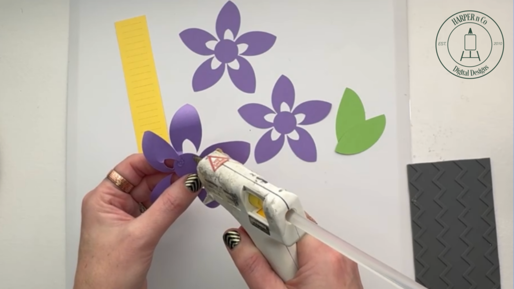 Gluing petals inward to assemble the first layer of a layered 3D paper flower