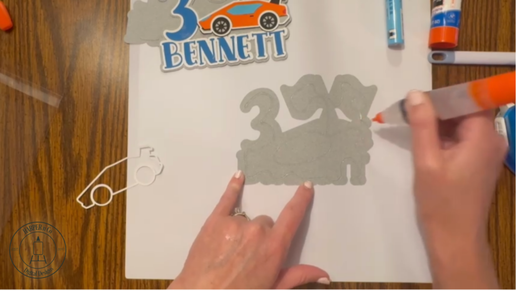 Multiple gray cardstock layers glued together with sticks attached to the back of a custom cake topper for stability.